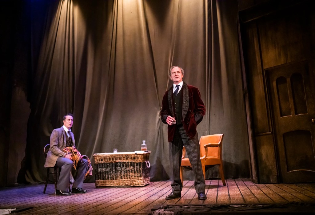 A photo of the stage show, with the two characters on a simple stage with two chairs and a basket.