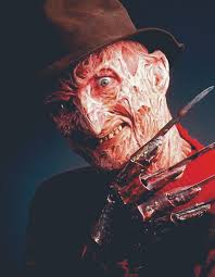 A disfigured man (Freddy) with severely burned skin wears a brown fedora and a red-and-green striped sweater. He grins menacingly, raising a gloved hand tipped with long metal blades.
